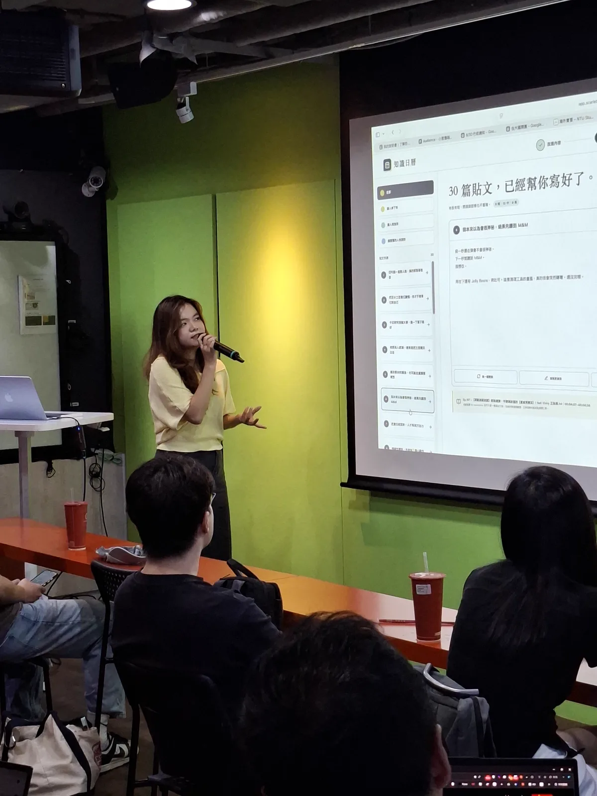 Scarlett 在 InternX 創業小聚台上分享，投影幕顯示她用 AI 做出的知識日曆網站